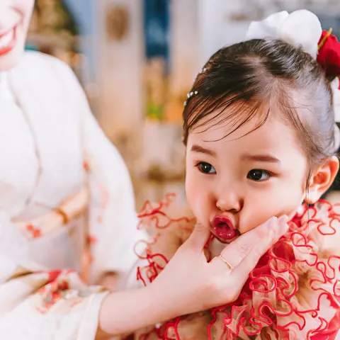 白い花の髪飾りとフリル衿の3歳の女の子とご両親