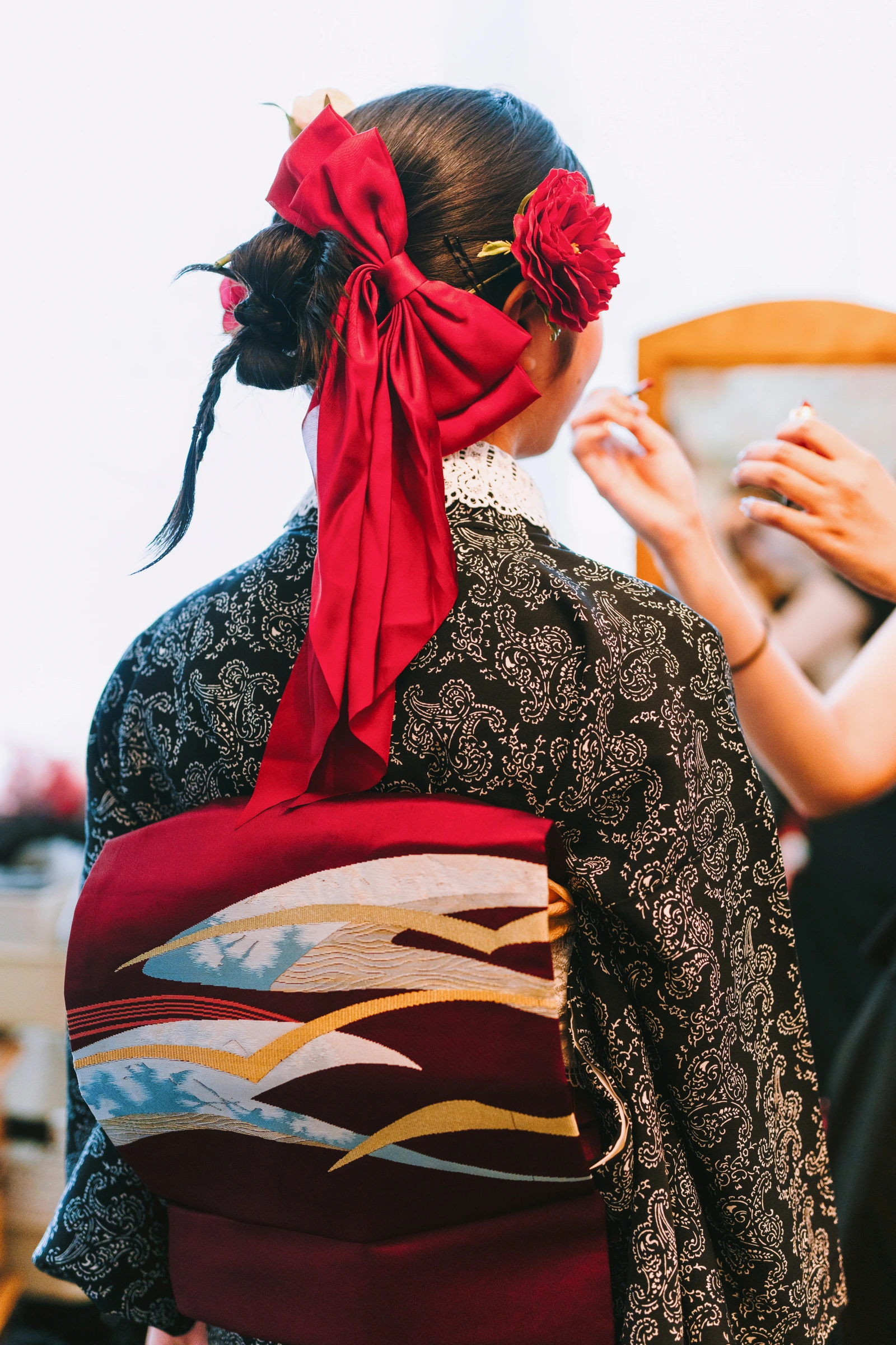 髪を結い上げて、赤いリボンと花かざりをつけたハーフ成人式のヘアセット